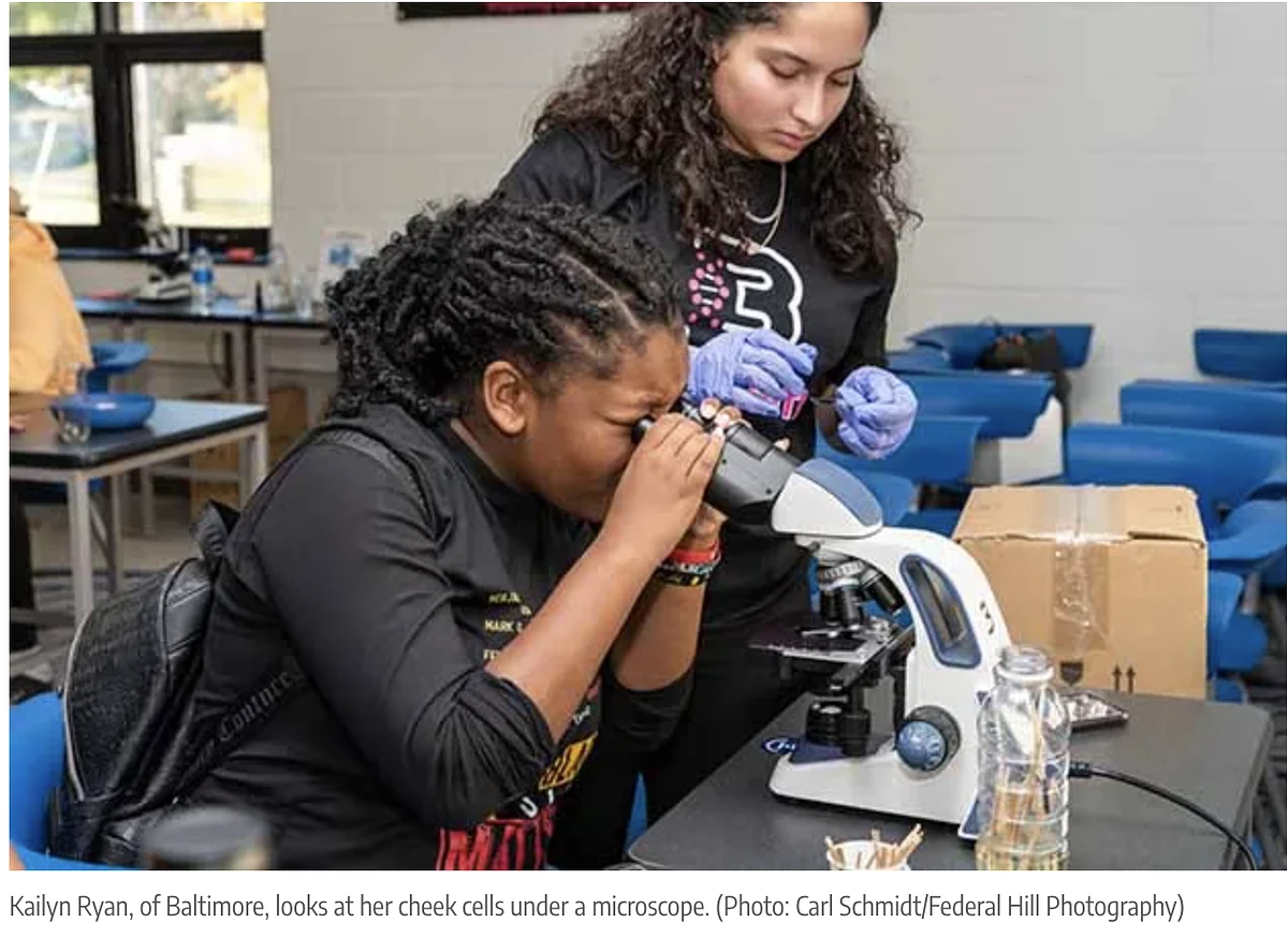 A student looks at her microscope at the expo