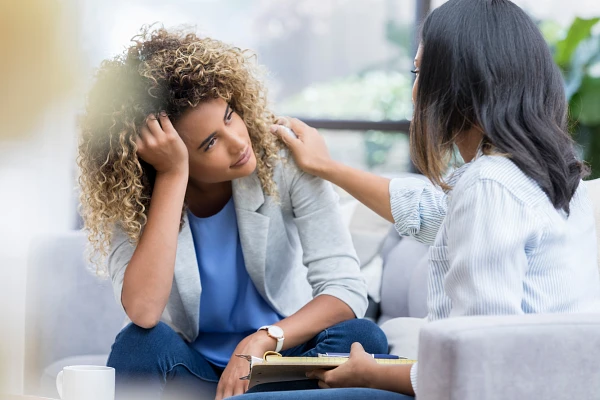 A woman offers comfort and support to another woman who appears to be distressed.